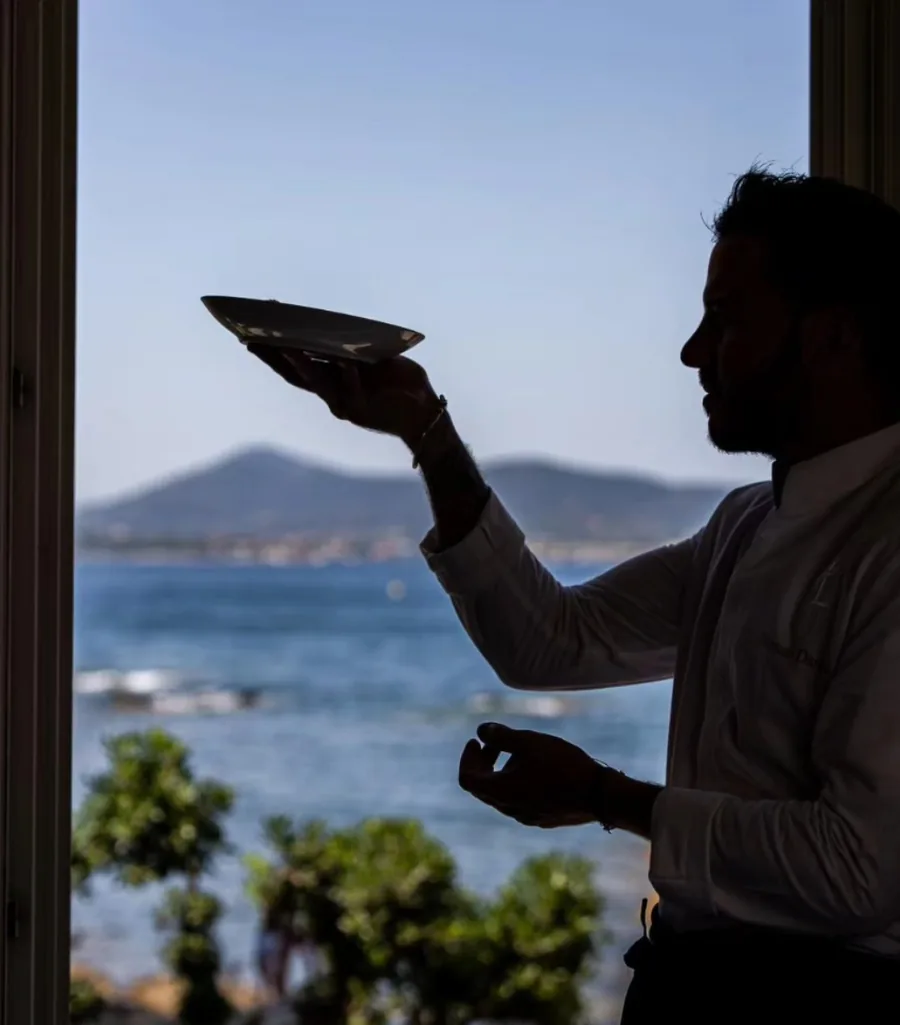 Silhouette de chef présentant une assiette face à la mer