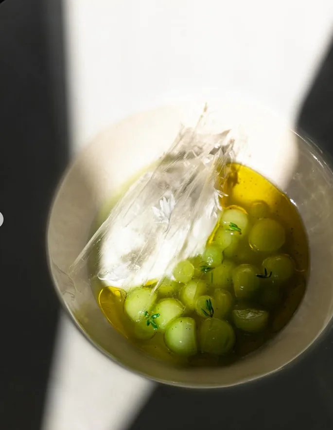Raisins verts et huile d'olive dans une assiette, lumière naturelle