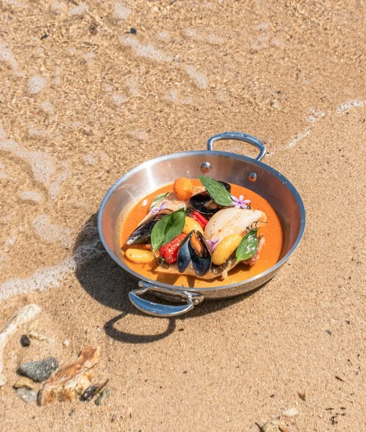 Bouillabaisse en cocotte posée sur le sable